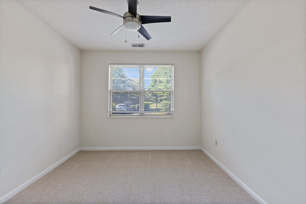 an empty room with a ceiling fan and a window