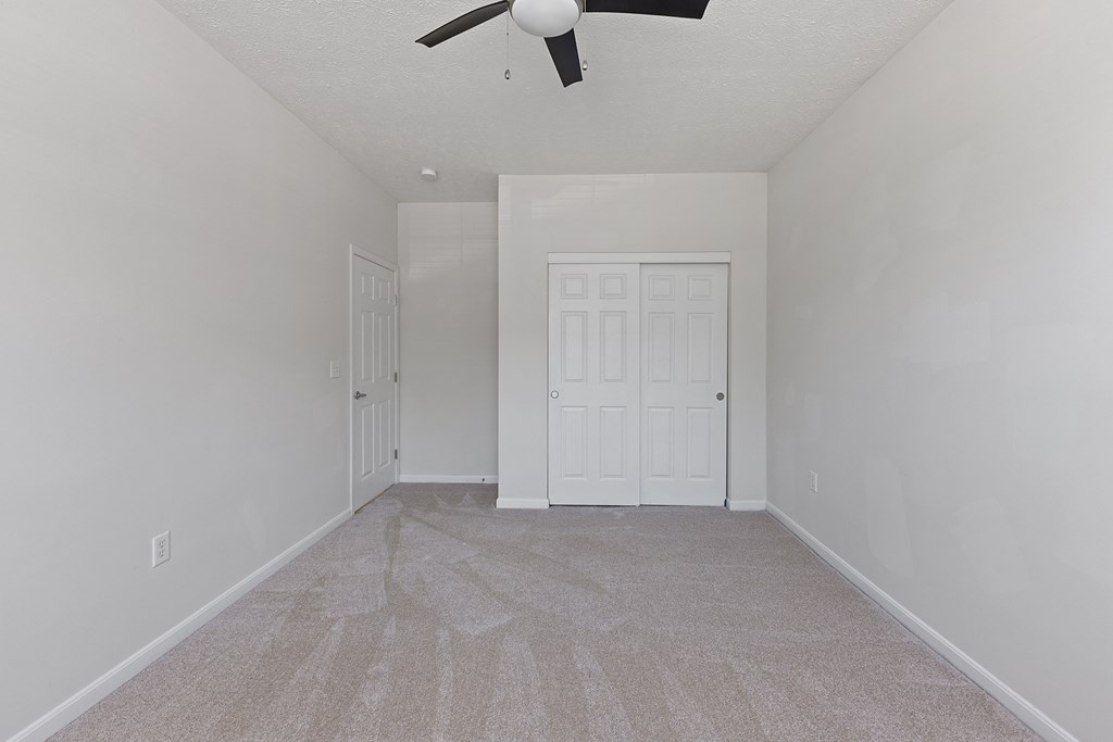an empty living room with a ceiling fan and a white door