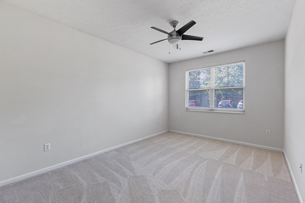 an empty living room with a ceiling fan and a window