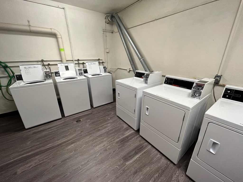 a row of washers and dryers in a room with wood floors