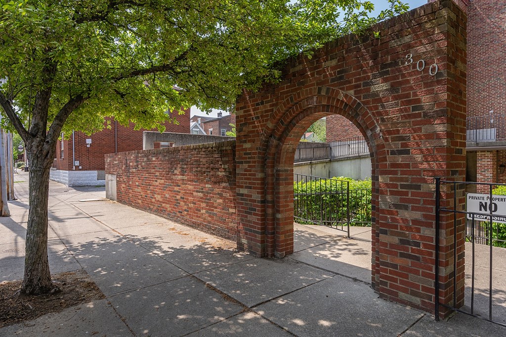 a brick wall with an arch next to a tree