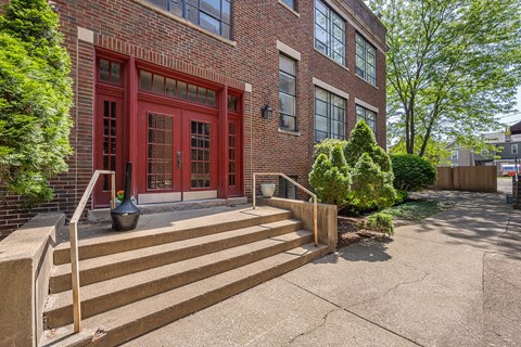 A red brick building with a set of stairs leading up to the front door.