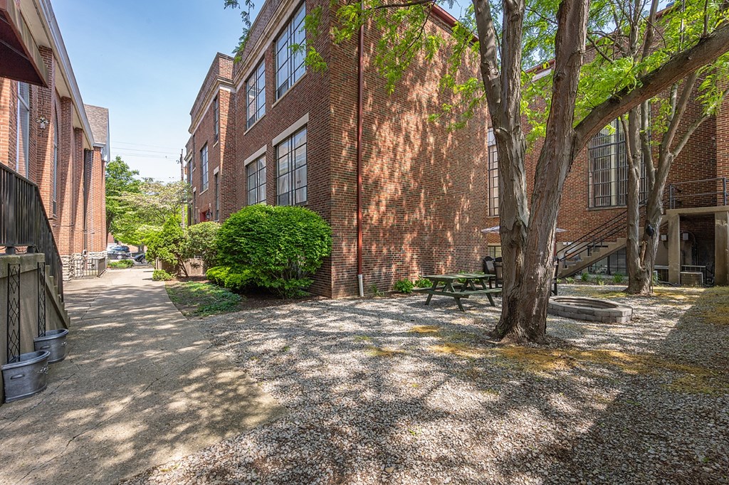 a courtyard between two brick buildings with a tree and a bench