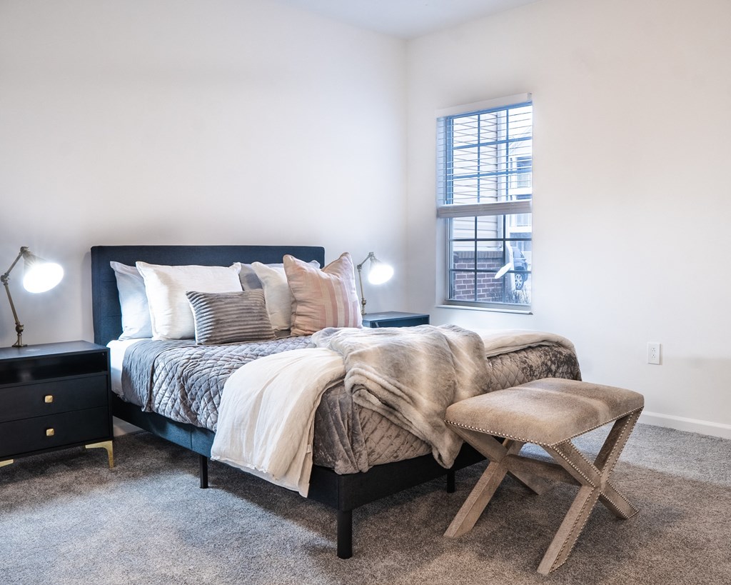 a bedroom with a bed and a stool in front of a window  at Waterstone Landing, Ohio, 43551
