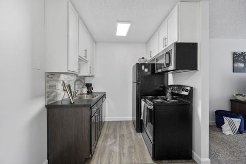 a small kitchen with white cabinets and black appliances
