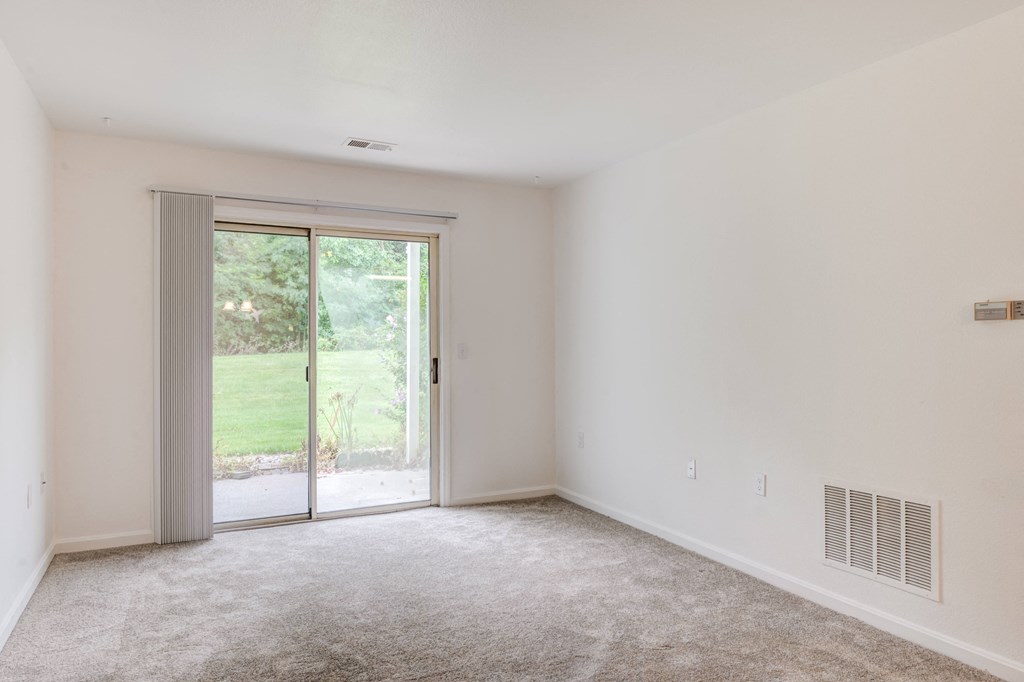 a living room with white walls and a sliding glass door