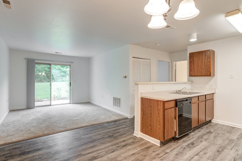 an empty kitchen and living room with a sliding glass door to a yard