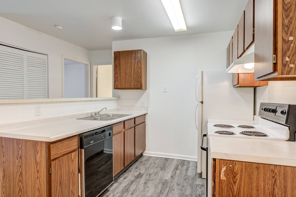 a kitchen with white countertops and wooden cabinets and a stainless steel refrigerator