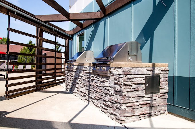 a patio with a grill and a wooden fence