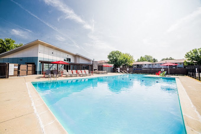 a large swimming pool with lounge chairs and umbrellas in front of a building
