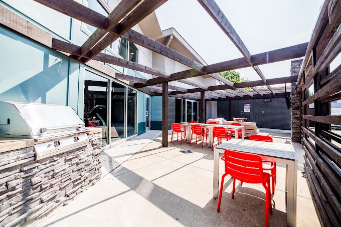 a patio with tables and chairs and a grill