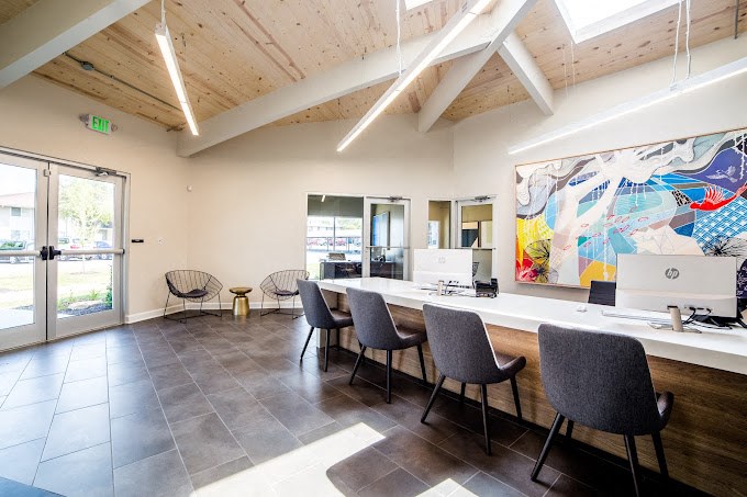 a room with a long table with chairs and a large painting on the wall