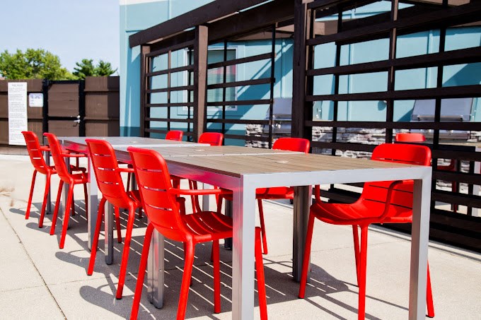 a long table with red chairs in front of a building
