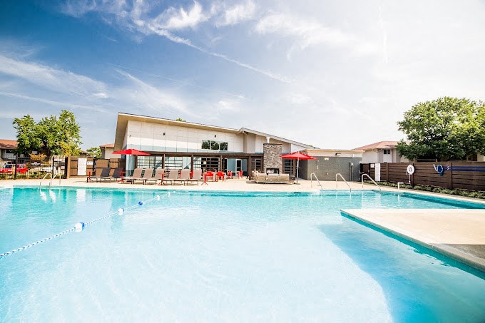 a large swimming pool with umbrellas and a building in the background