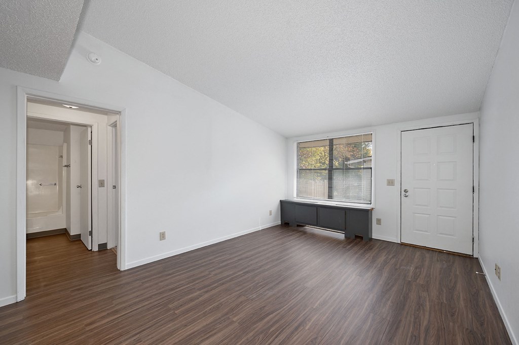 an empty living room with wood flooring and white walls