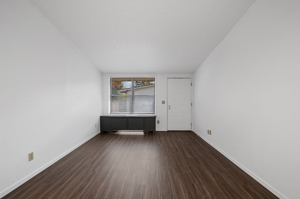 an empty living room with white walls and wood floors