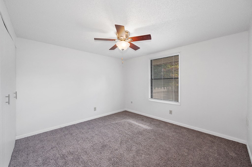 an empty living room with a ceiling fan and a window