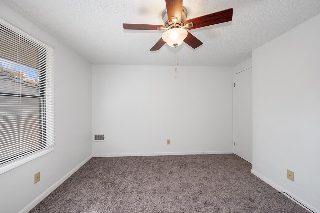 an empty room with a ceiling fan and a window