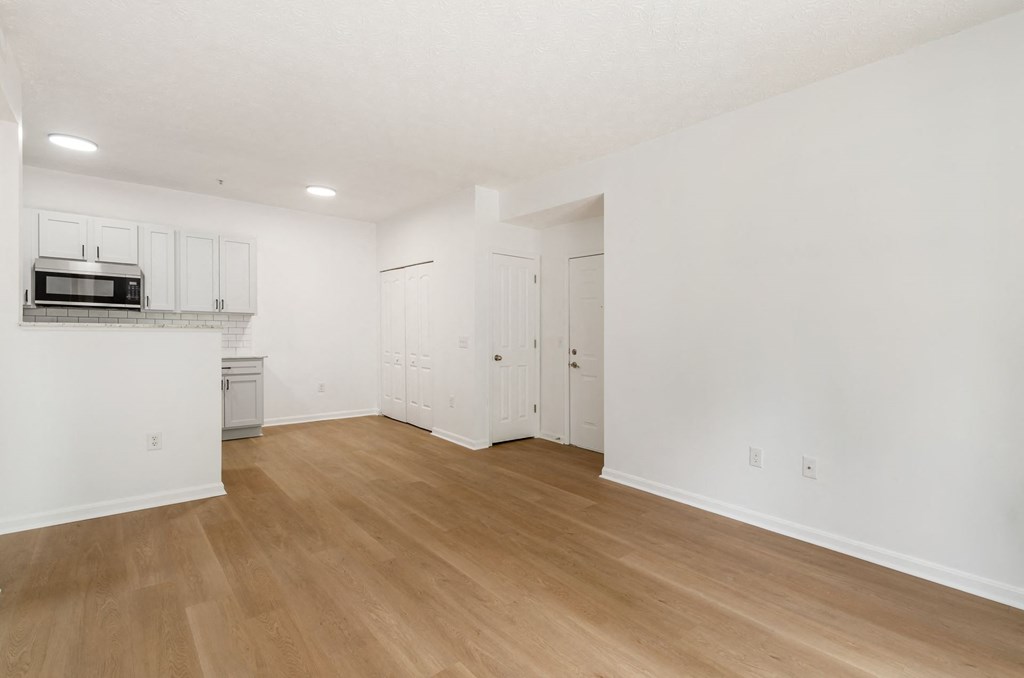 an empty living room and kitchen with white walls and wood floors at Prescott Place, Columbus, Ohio