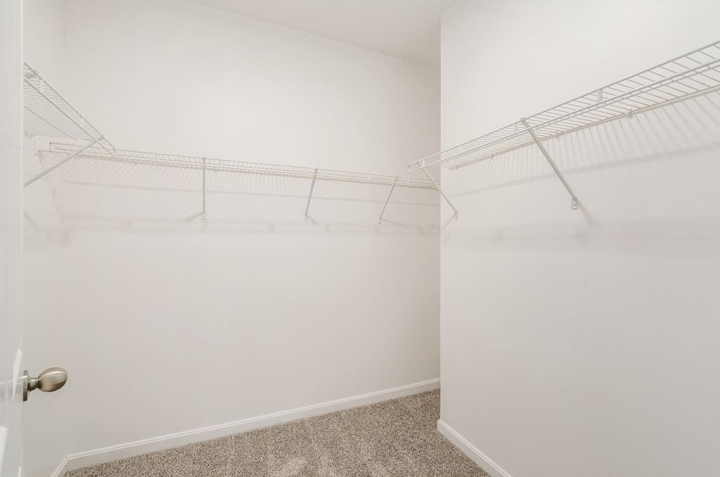a walk in closet with white walls and shelves and a glass door at Prescott Place, Columbus