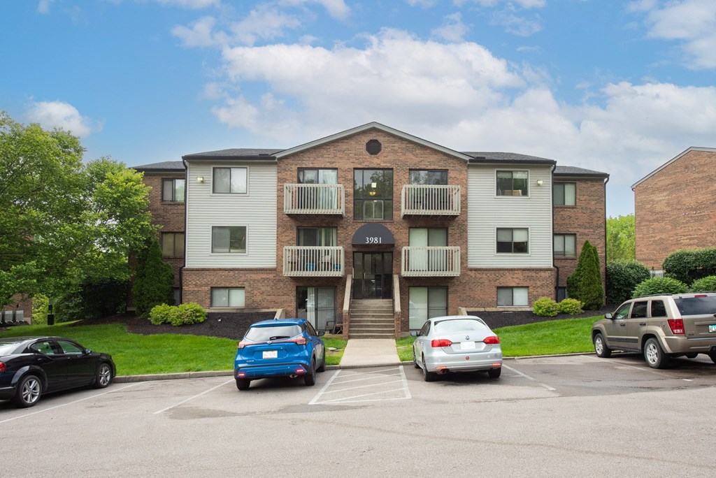 an apartment building with a parking lot and cars parked in front at The Woodridge Collection, Fairfield
