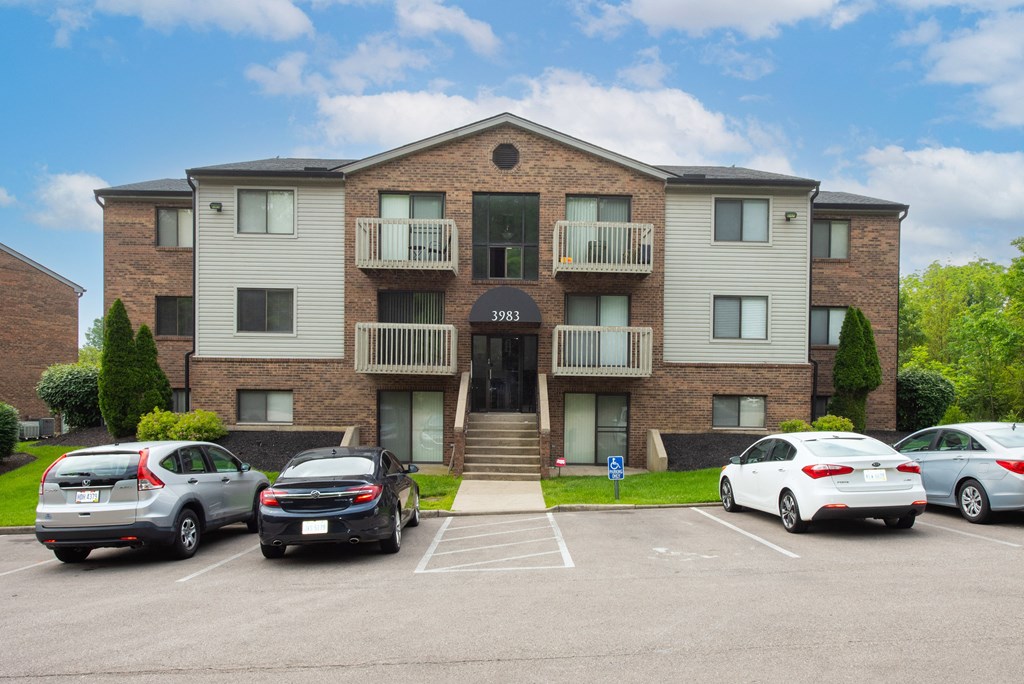 an apartment building with cars parked in front of it at The Woodridge Collection, Fairfield, OH 