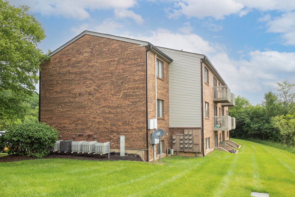 a brick apartment building with a green lawn and a blue sky at The Woodridge Collection, Fairfield, OH 45014