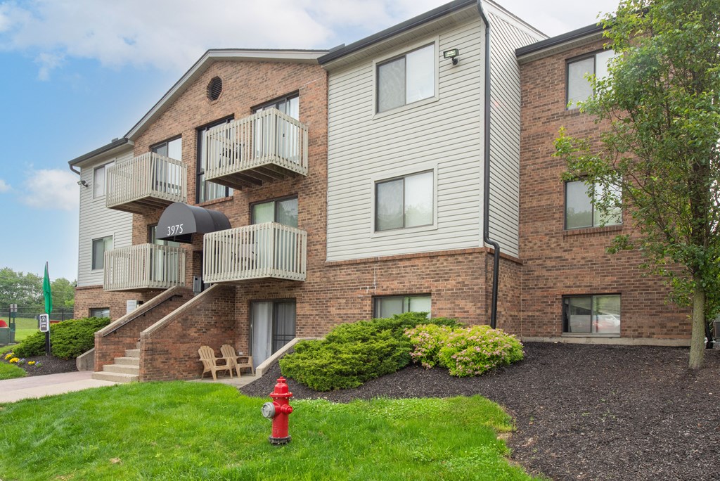a red fire hydrant in front of a brick apartment building at The Woodridge Collection, Fairfield, OH 45014