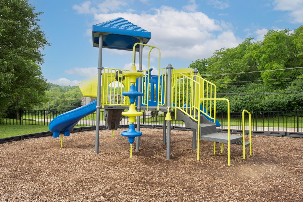 a playground with a blue and yellow swing set at The Woodridge Collection, Fairfield, OH 