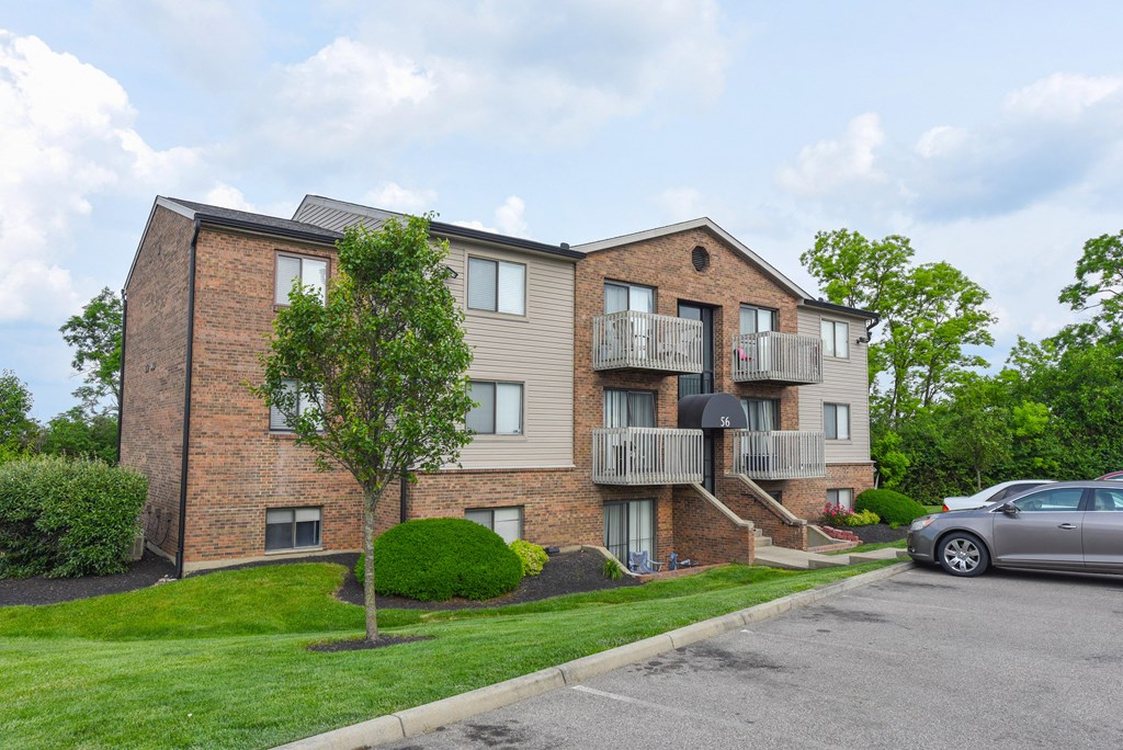 a brick apartment building with two balconies and a parking lot at The Woodridge Collection, Fairfield, OH 
