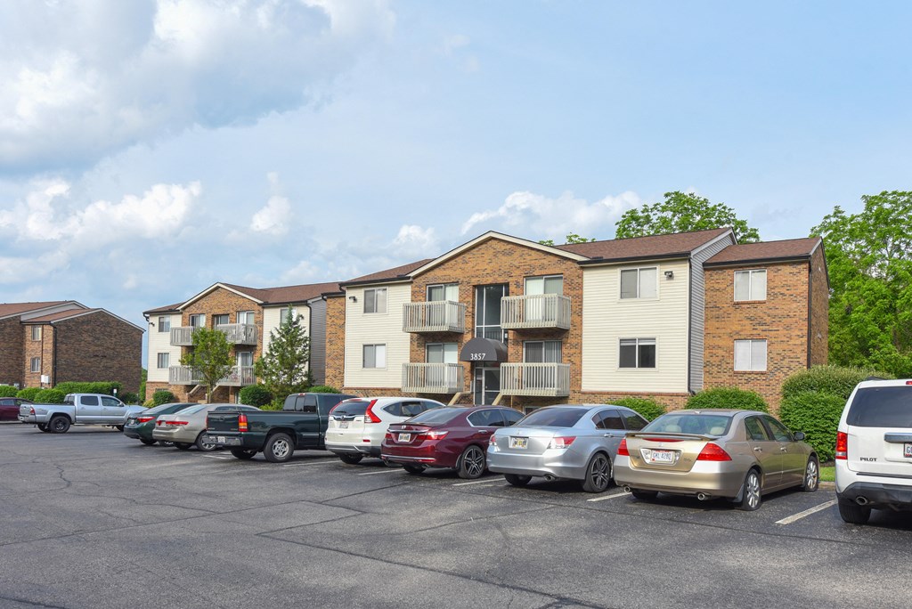 a parking lot with cars in front of an apartment building at The Woodridge Collection, Ohio