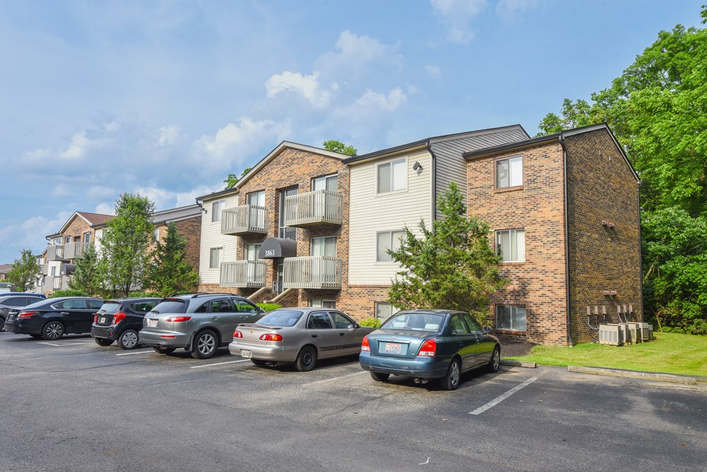 a parking lot with cars in front of an apartment building at The Woodridge Collection, Fairfield, OH 