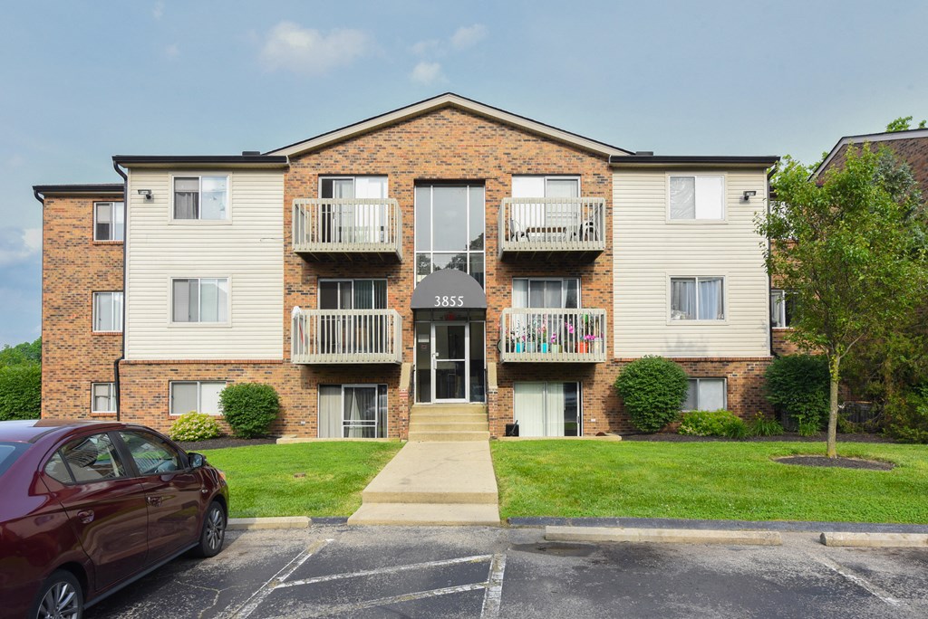 an apartment building with a red car parked in front of it at The Woodridge Collection, Fairfield, Ohio