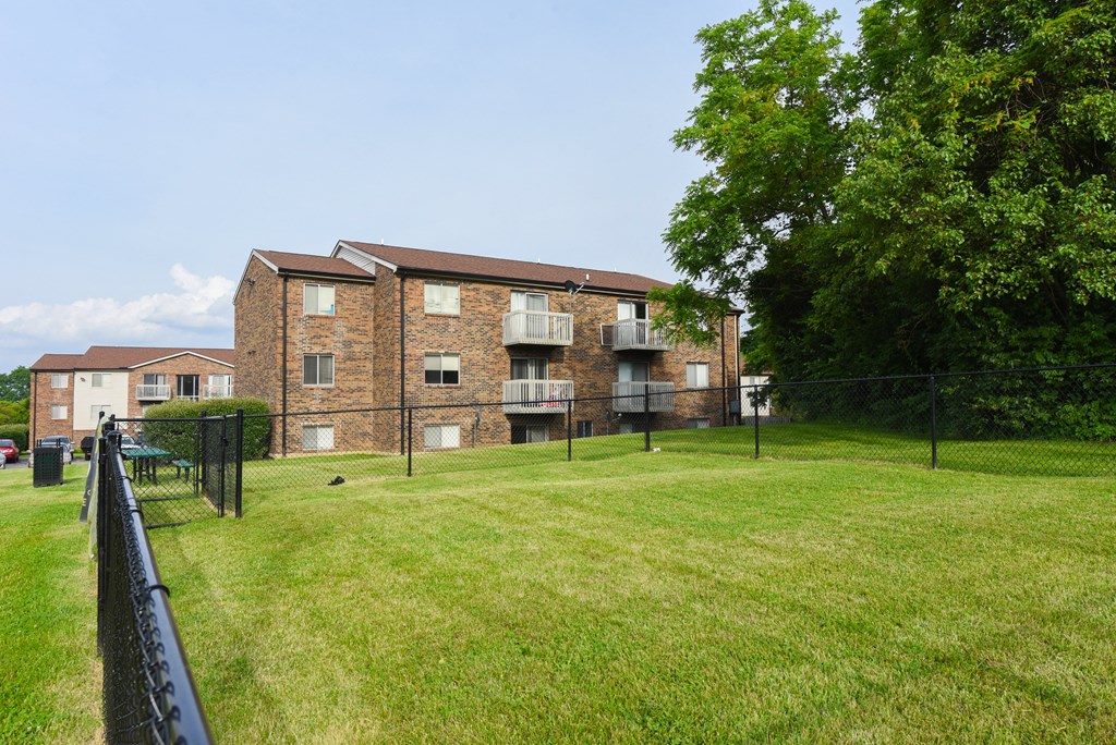 the back of an apartment building with a yard and a fence at The Woodridge Collection, Ohio, 45014