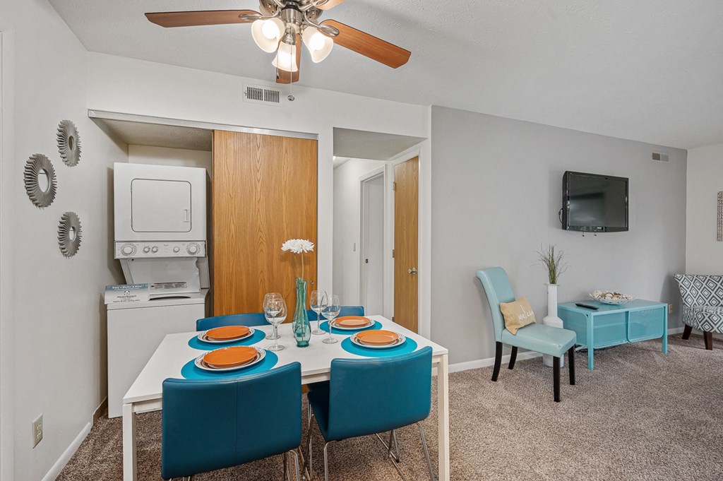 a dining area with a white table and blue chairs and a ceiling fan at The Woodridge Collection, Fairfield, OH 45014