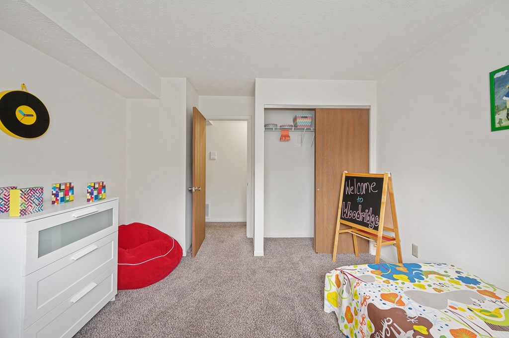 a bedroom with a white dresser and a bed with a red pillow at The Woodridge Collection, Fairfield Ohio