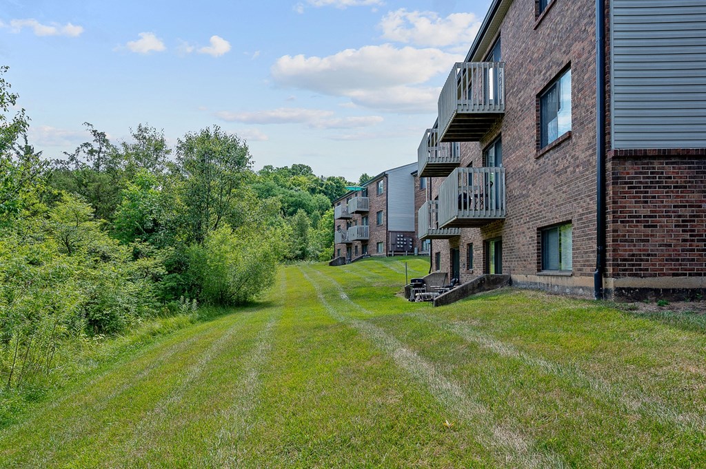 a grassy area with a brick building on the left and trees on the right at The Woodridge Collection, Fairfield