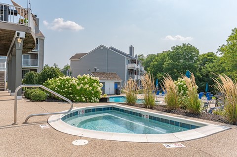 A small round pool surrounded by a concrete patio and a metal railing.