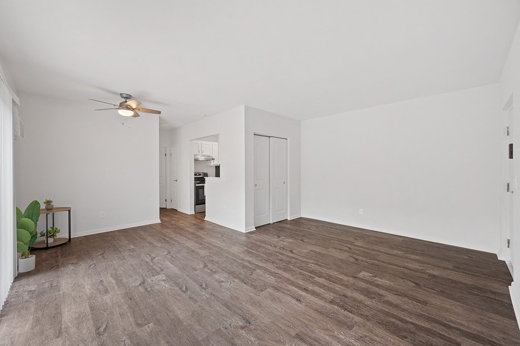 an empty living room with white walls and a ceiling fan