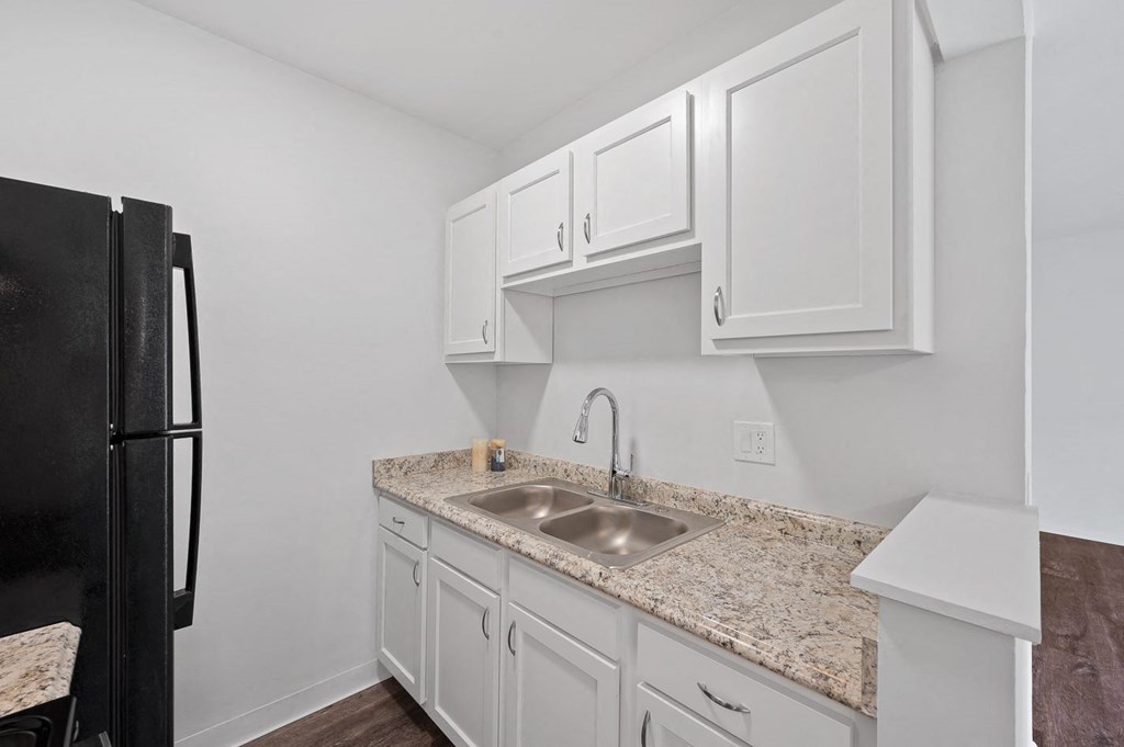 a kitchen with white cabinets and a sink and a refrigerator
