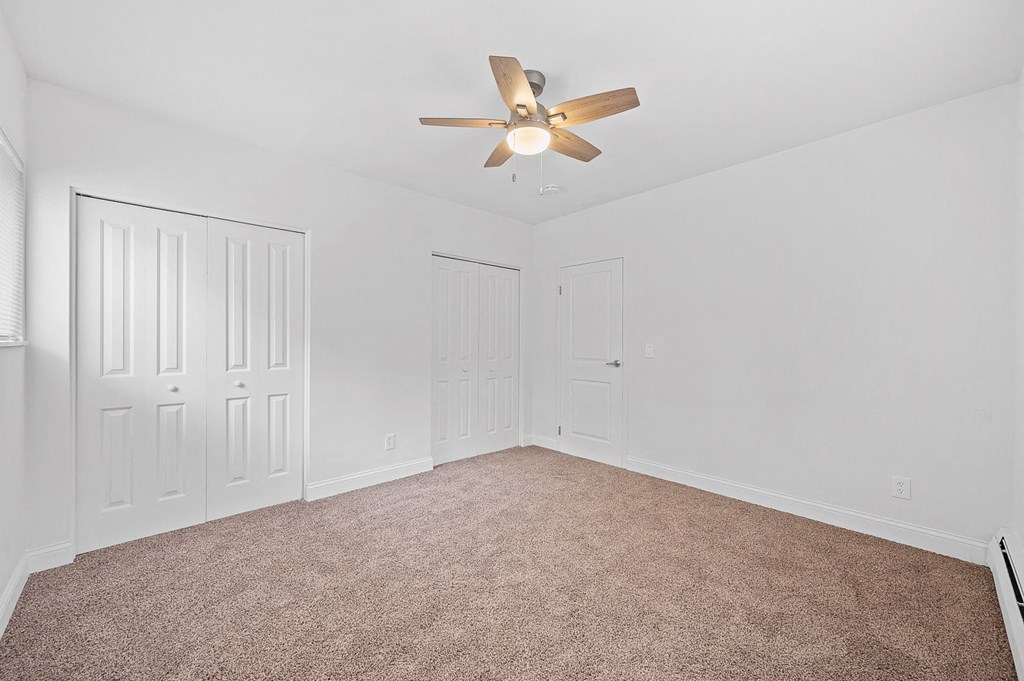 an empty bedroom with white walls and a ceiling fan