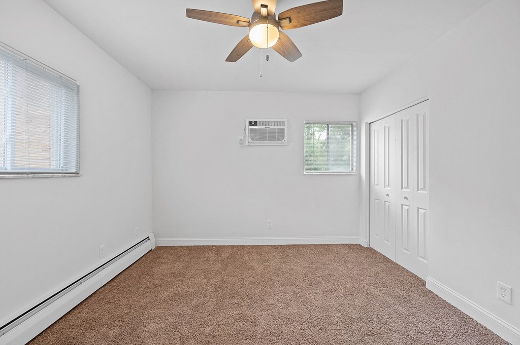 an empty bedroom with a ceiling fan and a window