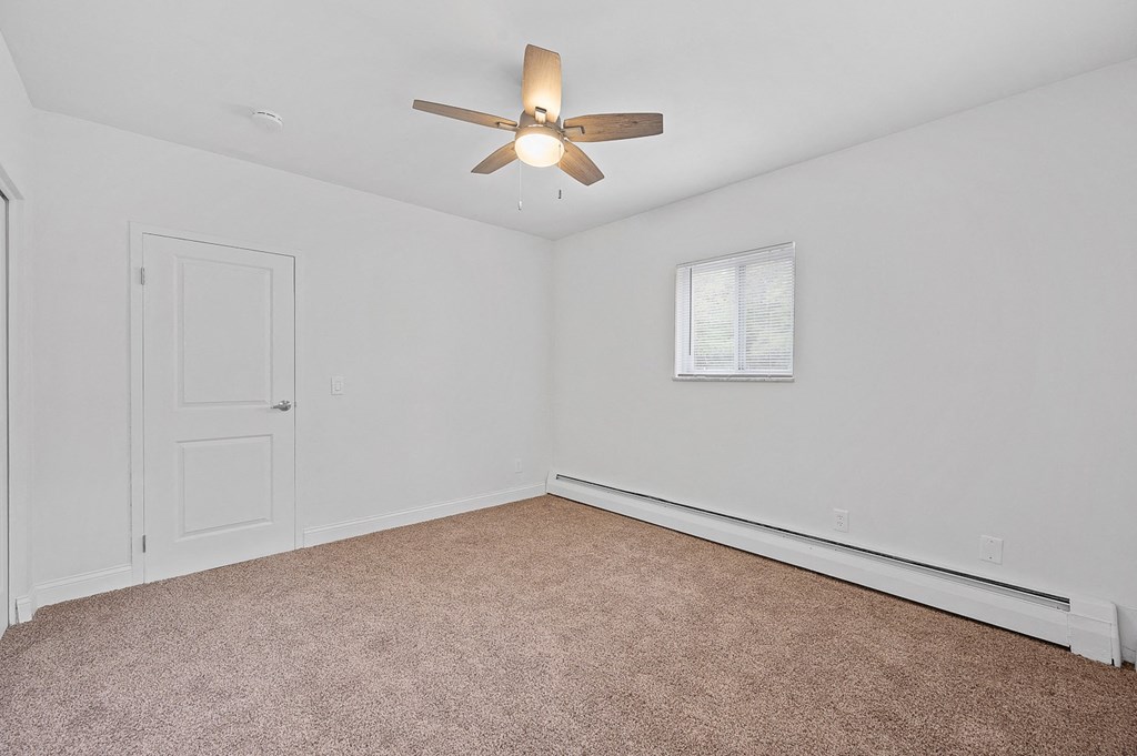 an empty room with a ceiling fan and a window