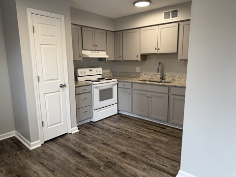 A kitchen with a white stove and cabinets.