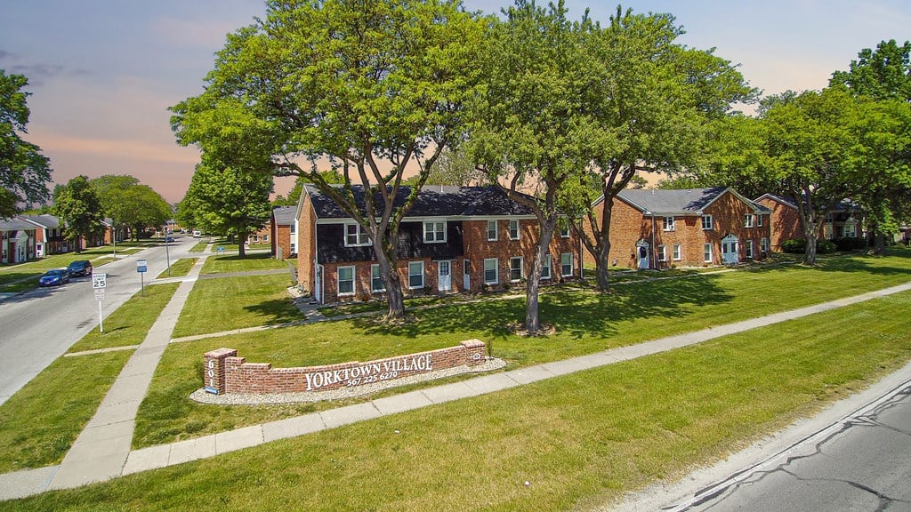 an aerial view of a brick house on the side of a street
