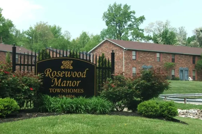 a sign for rosewood manor townhomes in front of a brick building