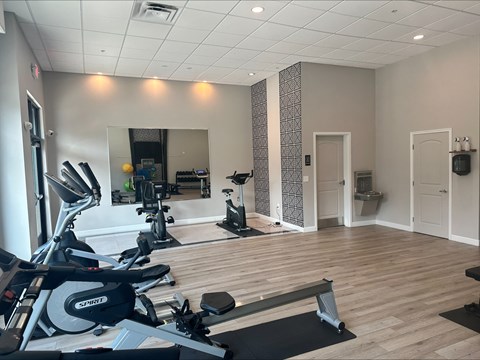 a gym with cardio machines and a mirror on the wall