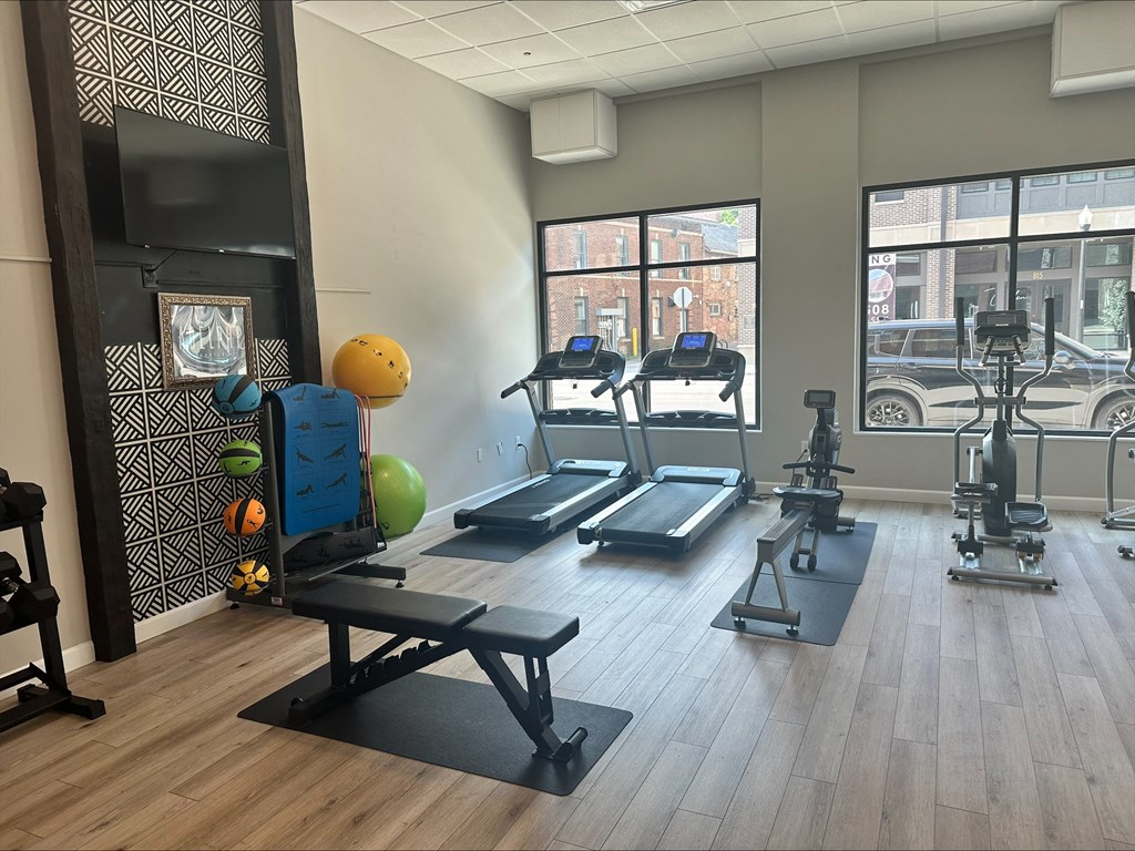 a gym with treadmills and weights on a wooden floor at Adelphi Quarter, Columbus, 43203