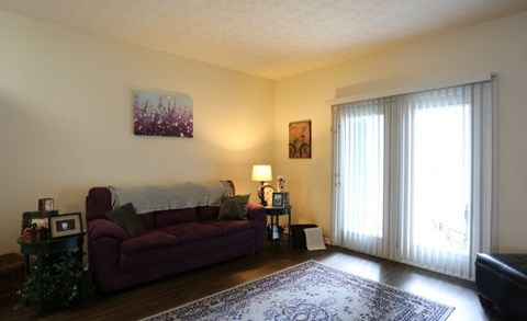 A living room with a red couch and a painting on the wall.