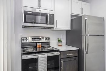 A modern kitchen with a stainless steel refrigerator, microwave, oven, and stove.